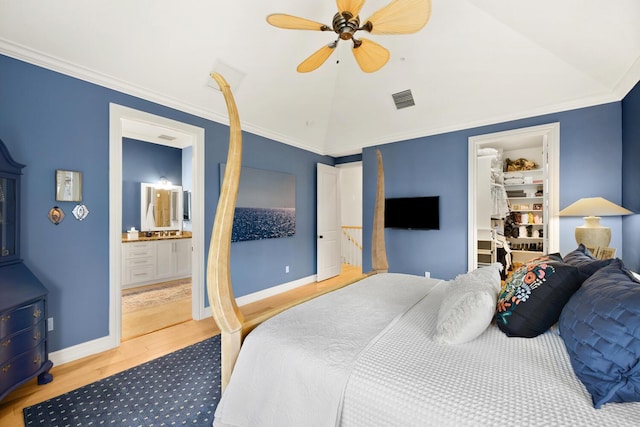 bedroom with a walk in closet, ensuite bath, ceiling fan, ornamental molding, and wood-type flooring