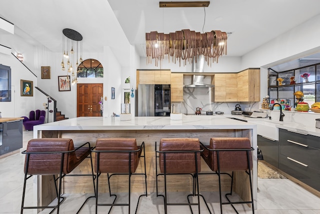 kitchen featuring decorative backsplash, stainless steel fridge, a kitchen breakfast bar, wall chimney exhaust hood, and pendant lighting