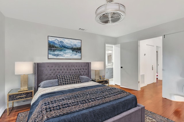 bedroom featuring connected bathroom and hardwood / wood-style flooring