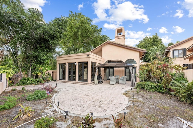 back of property featuring a gazebo and a patio area