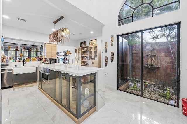 kitchen featuring light stone countertops, stainless steel dishwasher, hanging light fixtures, and sink