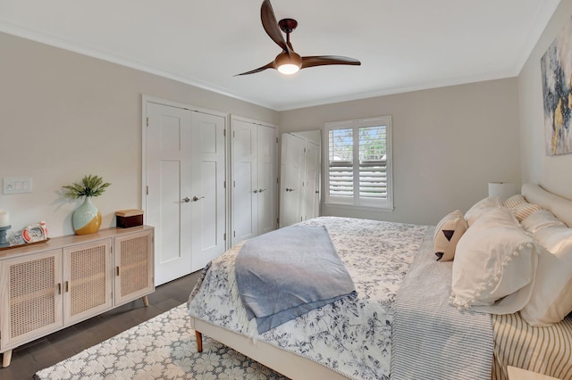 bedroom with two closets, ceiling fan, and dark hardwood / wood-style floors