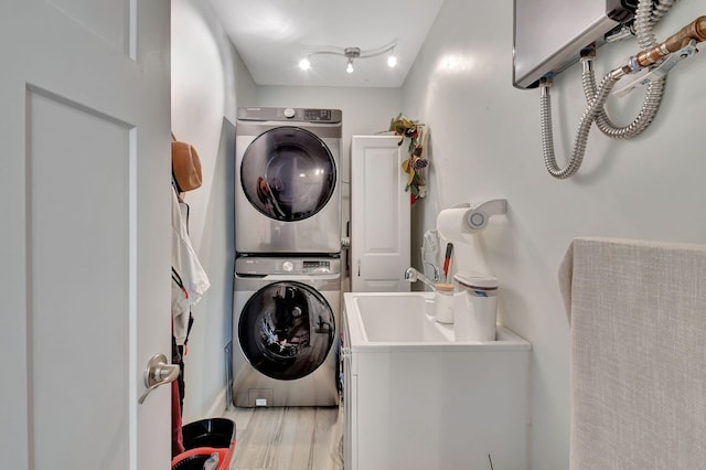 laundry room with stacked washer and dryer and light hardwood / wood-style flooring