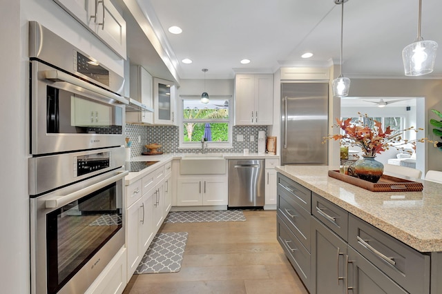 kitchen featuring white cabinetry, light hardwood / wood-style flooring, light stone countertops, and appliances with stainless steel finishes