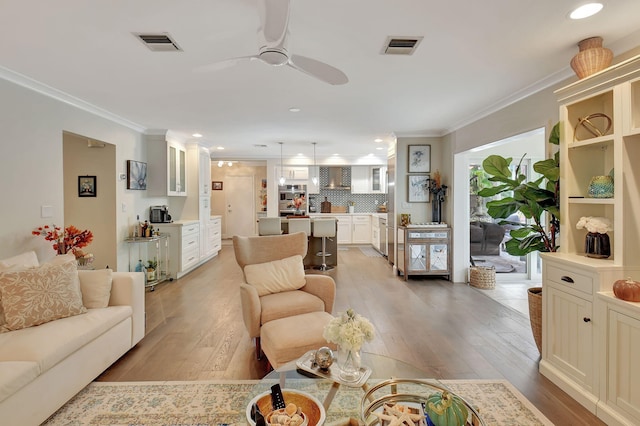 living room featuring light hardwood / wood-style floors, ceiling fan, and ornamental molding