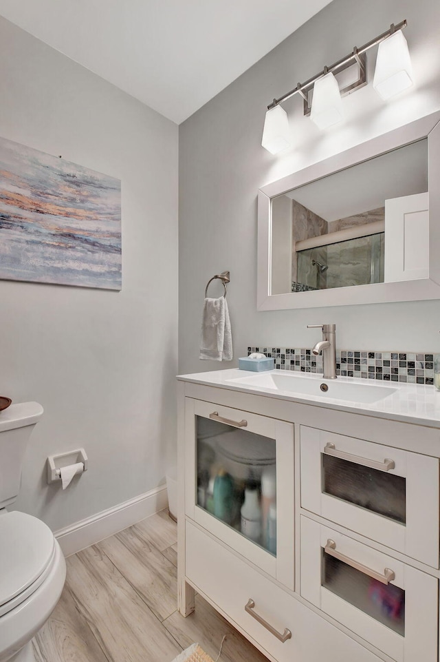 bathroom featuring walk in shower, hardwood / wood-style floors, vanity, and toilet