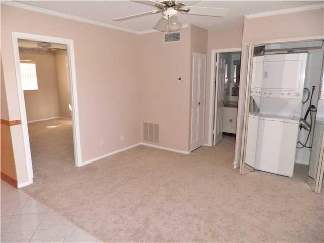 interior space featuring light carpet, crown molding, ceiling fan, and stacked washer / drying machine