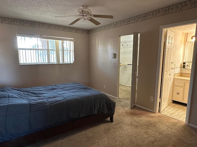 carpeted bedroom with ensuite bath, ceiling fan, and a textured ceiling