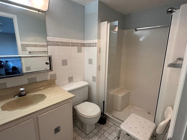 bathroom featuring a textured ceiling, vanity, a shower, tile walls, and toilet