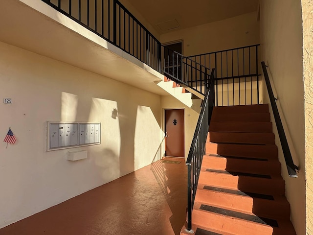 staircase with concrete flooring and a mail area