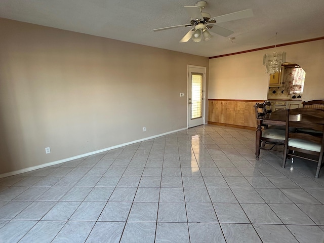 unfurnished dining area with wooden walls, light tile patterned flooring, and ceiling fan with notable chandelier