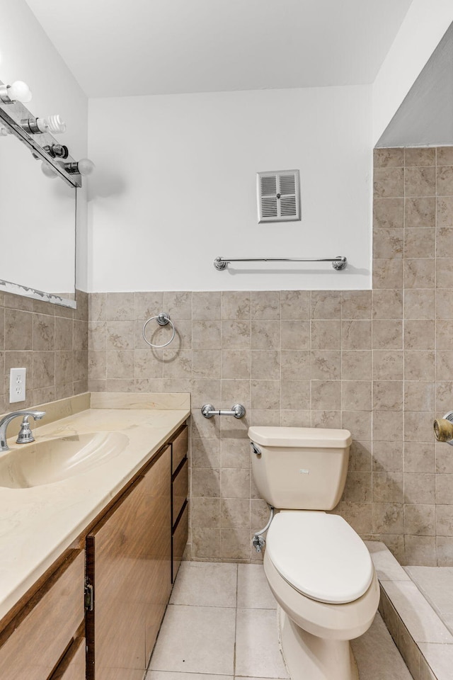 bathroom featuring toilet, vanity, tile patterned floors, and tile walls