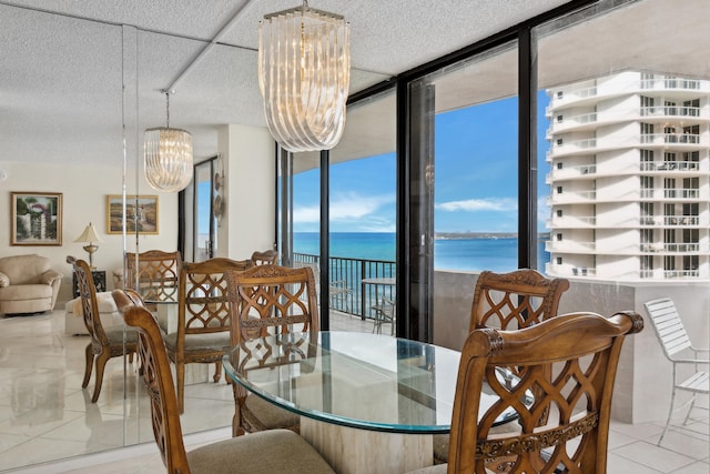 dining area featuring expansive windows, a textured ceiling, light tile patterned floors, a water view, and an inviting chandelier