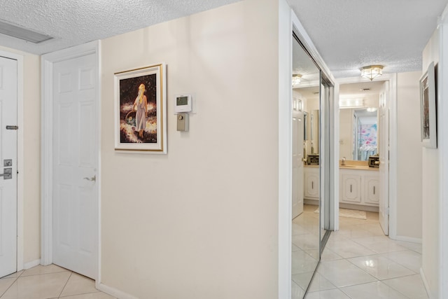 hall featuring sink, a textured ceiling, and light tile patterned flooring