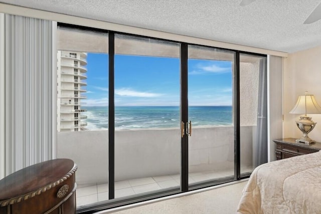 bedroom with a view of the beach, a textured ceiling, and a water view