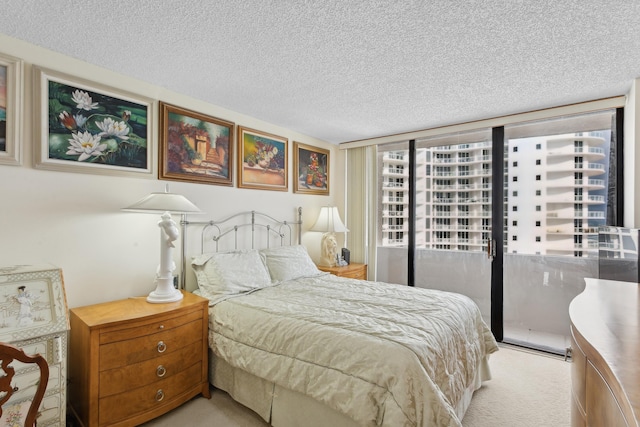 bedroom featuring light carpet, a textured ceiling, and a wall of windows