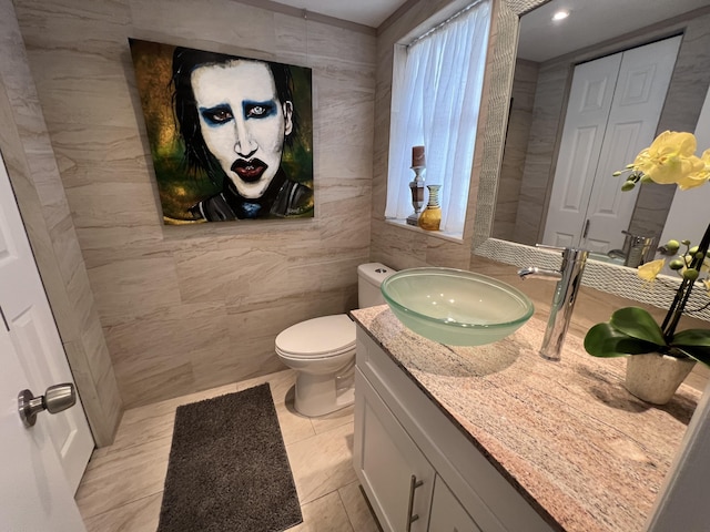 bathroom featuring toilet, tile walls, and vanity