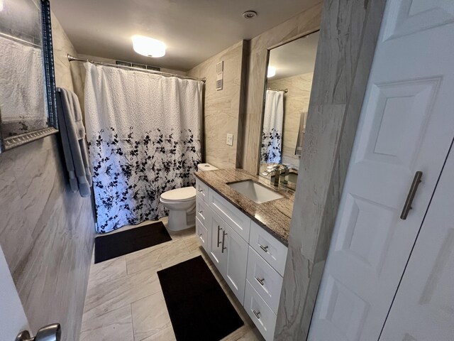 bathroom with a shower with curtain, vanity, toilet, and tile walls