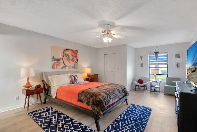 bedroom with wood-type flooring, a textured ceiling, a closet, and ceiling fan