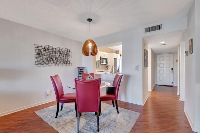 dining area featuring hardwood / wood-style flooring, sink, and a textured ceiling