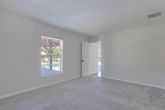 carpeted empty room with a textured ceiling