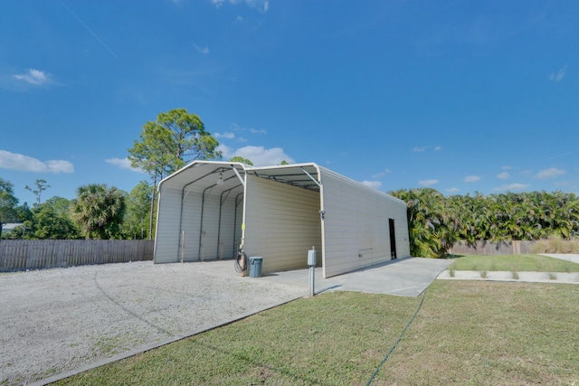 view of outdoor structure with a carport and a lawn