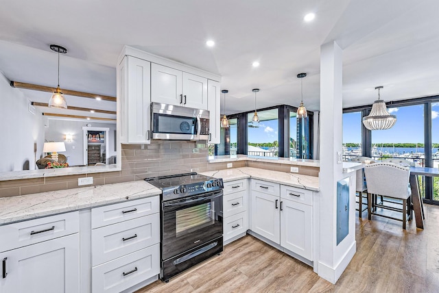 kitchen featuring pendant lighting, white cabinets, and black range with electric stovetop