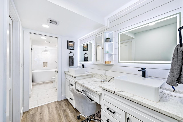 bathroom with wood-type flooring, vanity, toilet, and a bathing tub