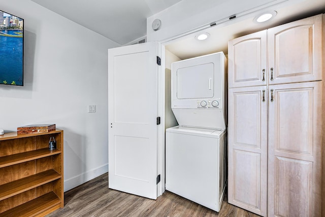 laundry area with stacked washer / drying machine and dark wood-type flooring