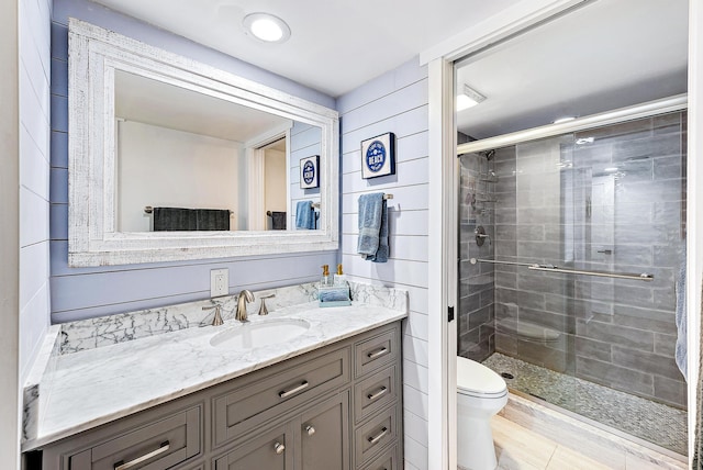 bathroom with vanity, toilet, and a shower with door