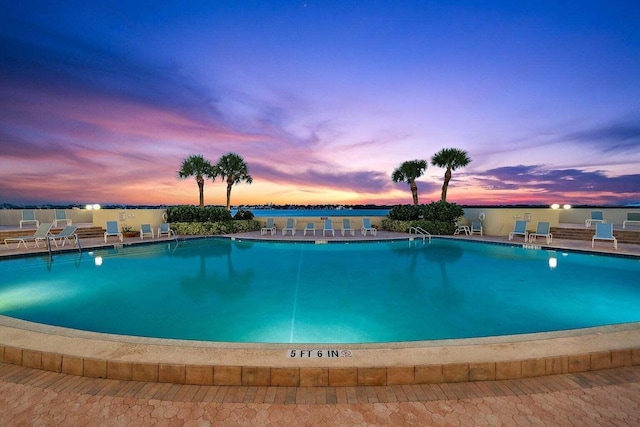 pool at dusk featuring a patio