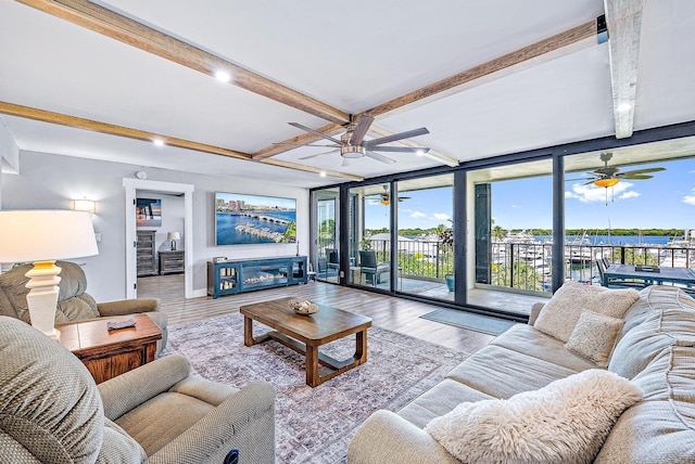 living room with light hardwood / wood-style flooring, beamed ceiling, and a wall of windows