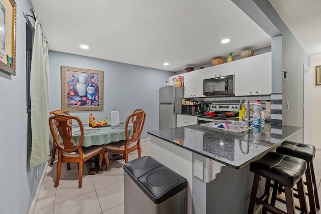 kitchen featuring white cabinetry, sink, stainless steel appliances, tasteful backsplash, and a breakfast bar area