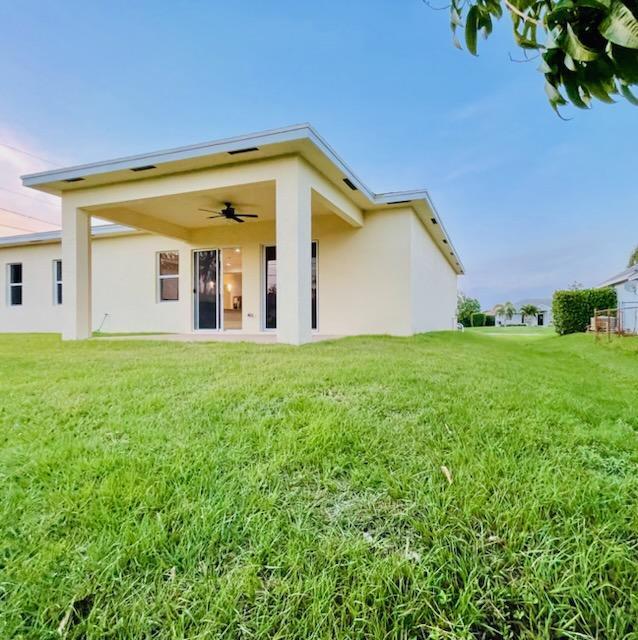 back of house with a lawn and ceiling fan