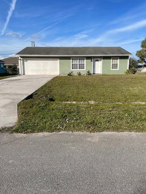 ranch-style home with a garage and a front lawn