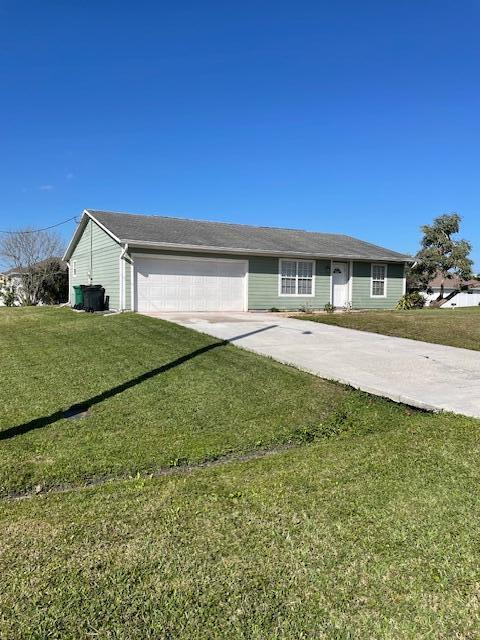 single story home with a front yard, concrete driveway, and an attached garage