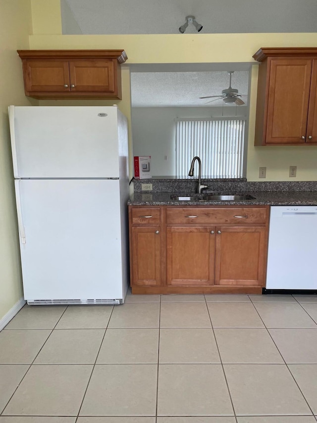 kitchen featuring ceiling fan, sink, light tile patterned flooring, white appliances, and dark stone countertops