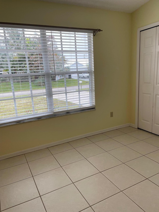 unfurnished bedroom with multiple windows, a closet, and light tile patterned floors