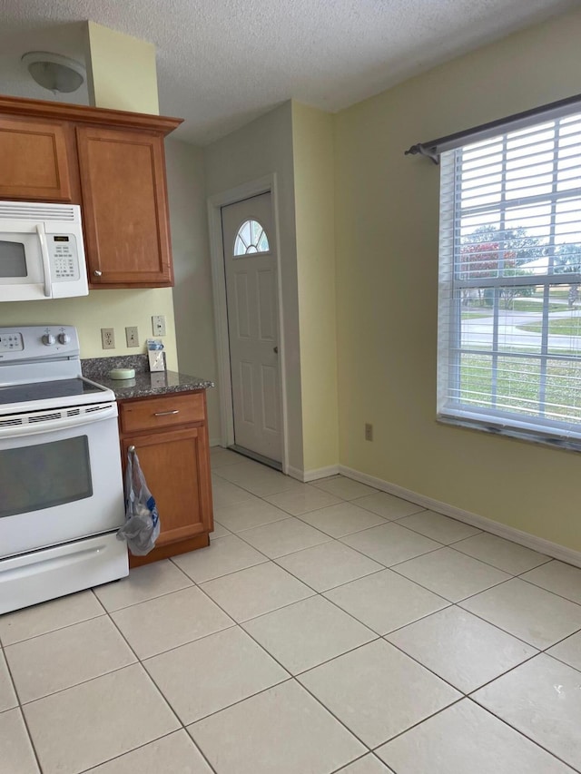 kitchen with white appliances, light tile patterned floors, a wealth of natural light, and a textured ceiling