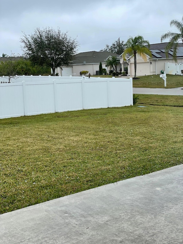 view of yard featuring fence, driveway, and an attached garage