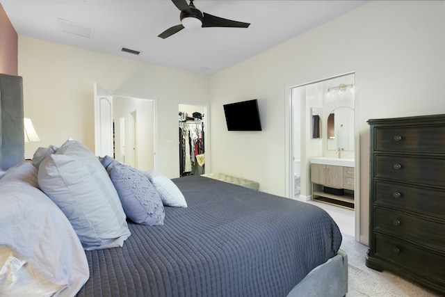 carpeted bedroom featuring a walk in closet, ensuite bathroom, a closet, and ceiling fan