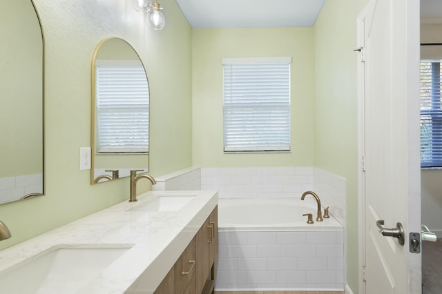 bathroom featuring a relaxing tiled tub and vanity