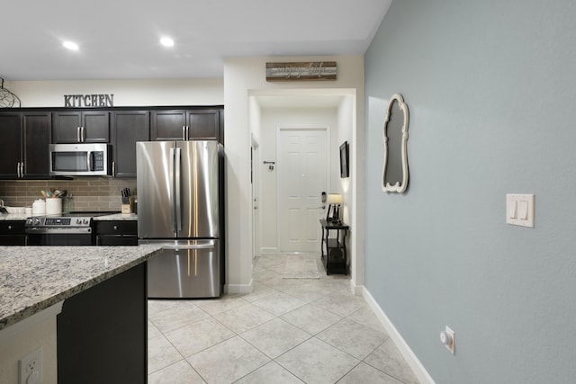 kitchen with light tile patterned flooring, light stone counters, backsplash, and appliances with stainless steel finishes