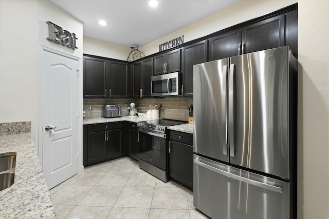 kitchen with backsplash, light stone counters, light tile patterned floors, and appliances with stainless steel finishes