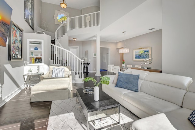 living room featuring a notable chandelier, light wood-type flooring, and a towering ceiling