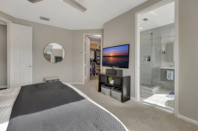 bedroom featuring ensuite bathroom, ceiling fan, light colored carpet, and a spacious closet