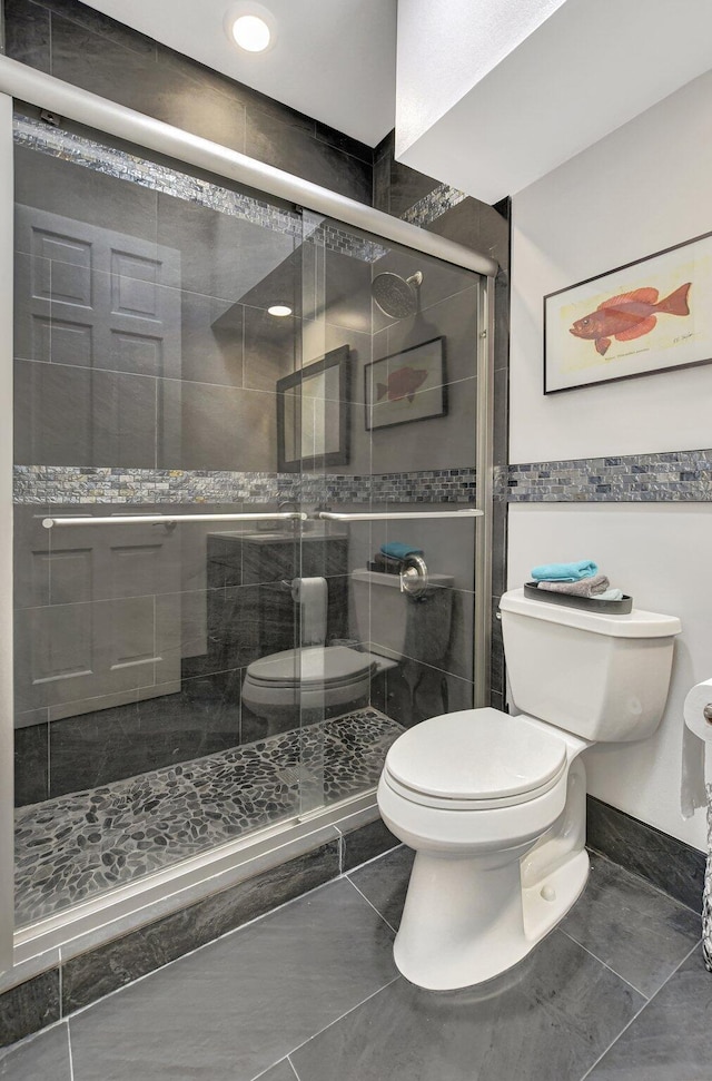 bathroom featuring walk in shower, tile patterned flooring, and toilet