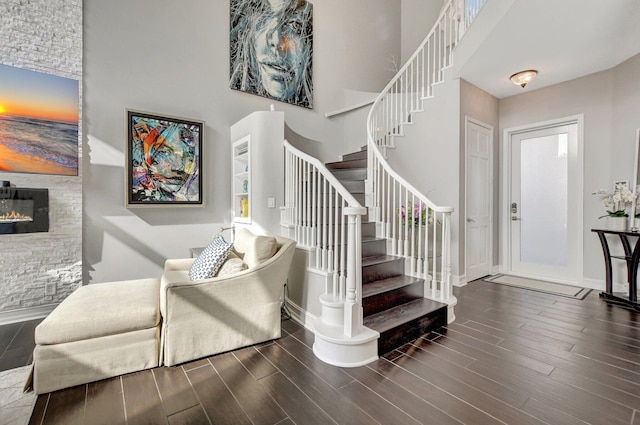 stairs with a fireplace, a towering ceiling, and wood-type flooring