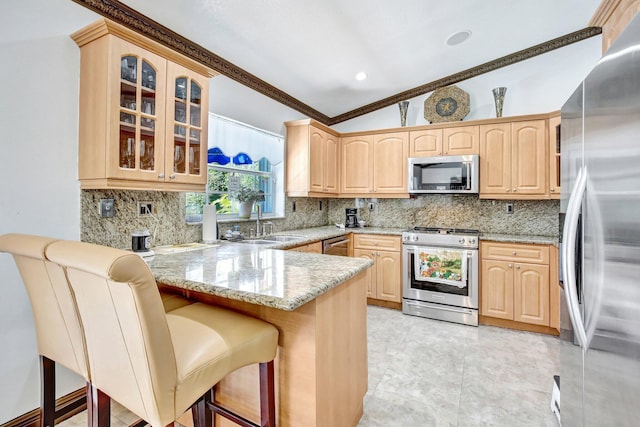 kitchen with kitchen peninsula, light stone counters, a breakfast bar, stainless steel appliances, and vaulted ceiling