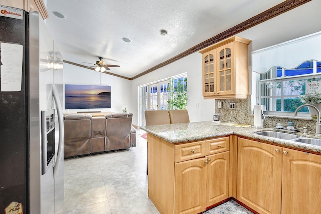 kitchen featuring sink, vaulted ceiling, stainless steel fridge with ice dispenser, a textured ceiling, and kitchen peninsula